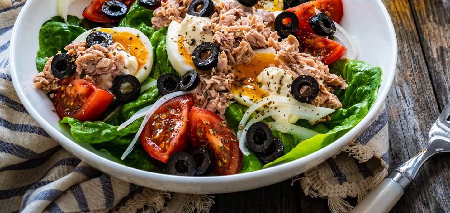 A nicoise salad served on a white plate.