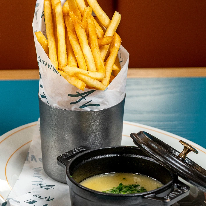 a container of french fries and soup on a plate