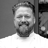 Chef Tim Hollingsworth smiling in his chef’s white uniform